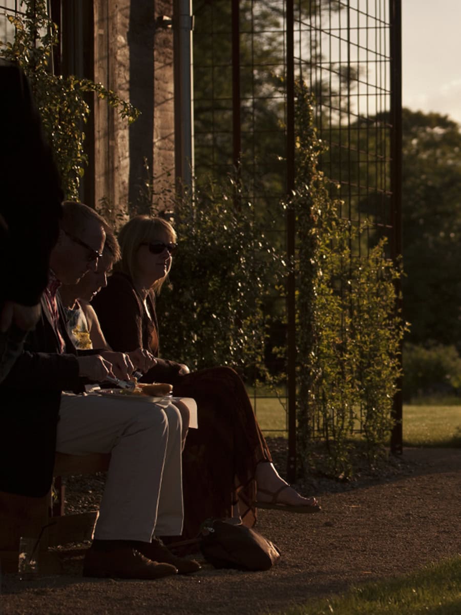 The Gillyflower guests seated outdoors at golden hour beside climbing plants and estate garden trellis